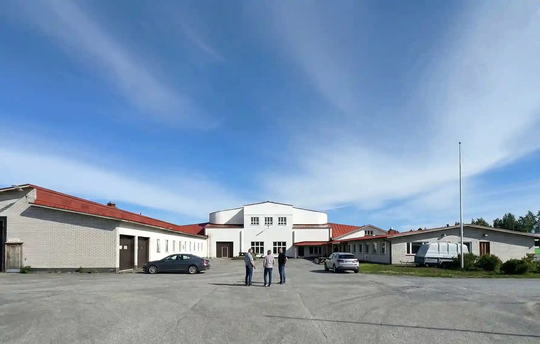 The Forsnäs Energy Park building in Kruunupyy, a long white building with a red roof and a central tower, under a blue sky.